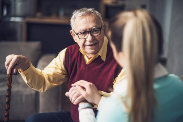 A caregiver holding a senior client's hand during a care visit